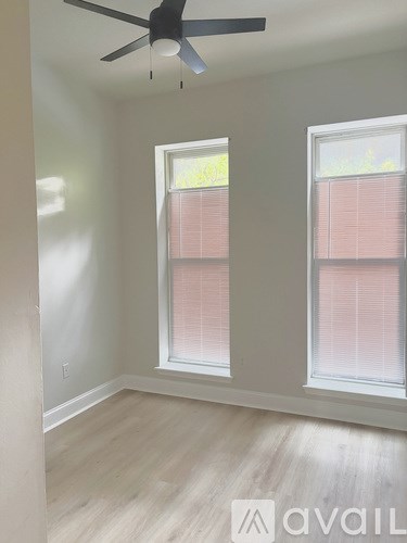 A room with a ceiling fan and two windows.