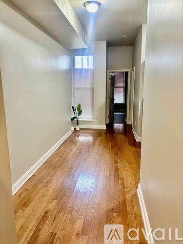 A hallway with wooden floors and white walls.