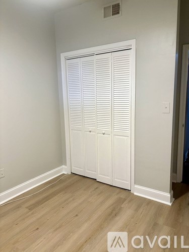 A white closet with wooden floors and a white door.
