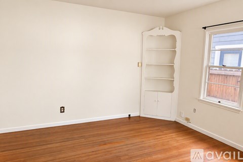 A room with a wooden floor and a large white shelf unit.