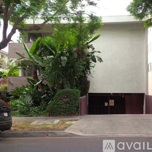 A black car is parked on the street in front of a house.