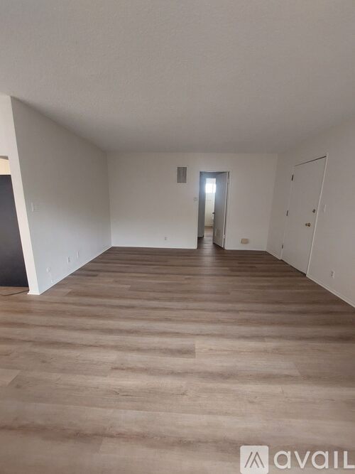 A spacious room with wooden flooring and white walls.