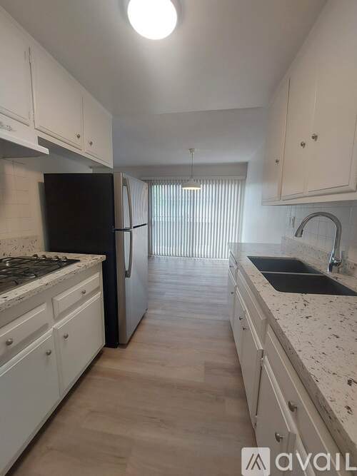 A kitchen with white cabinets and a black fridge.