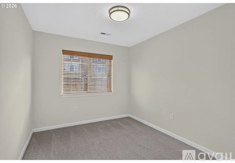 A room with a window covered by blinds and carpet on the floor.