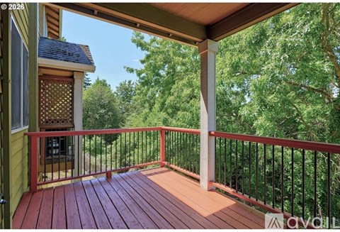 A wooden deck with a metal railing and a view of trees.