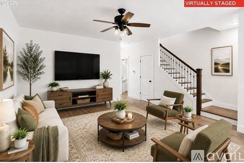 A living room with a television, a staircase, and a ceiling fan.