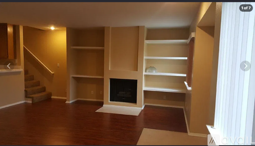 A living room with a fireplace and a staircase.
