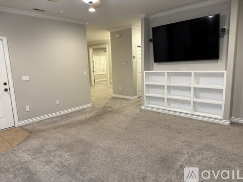A living room with a television and built-in shelves.