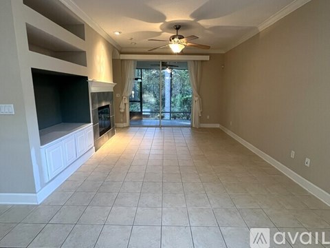 A spacious living room with a television and a sliding glass door leading to a balcony.