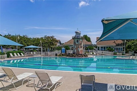 A pool with chairs and a lighthouse in the background.