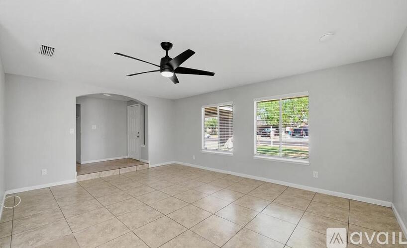 A spacious room with a ceiling fan and tiled flooring.