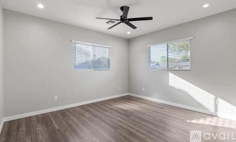 A room with a ceiling fan and two windows.