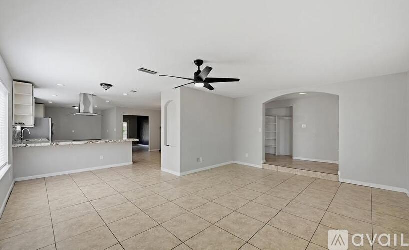 A spacious room with a ceiling fan and tiled flooring.