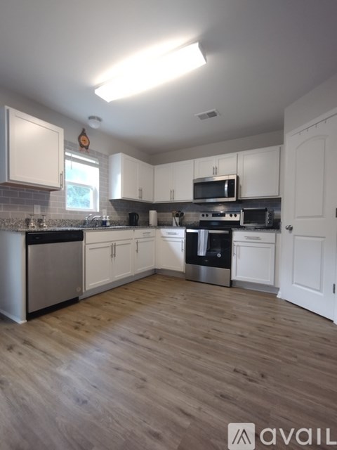 A kitchen with white cabinets and wooden floors.