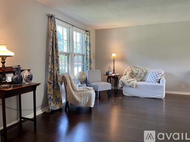 A living room with a white couch, a chair, and a table with vases on it.