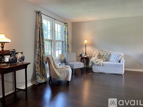 A living room with a white couch, a chair, and a table with vases on it.