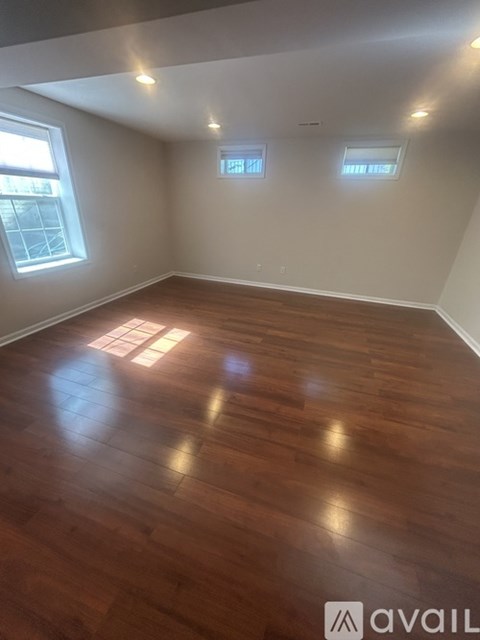 A room with wooden flooring and two windows.