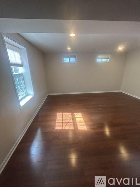 A room with wooden flooring and two windows.