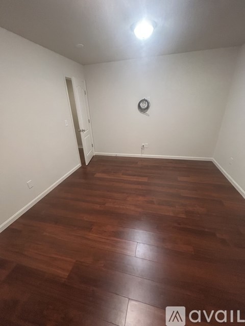 A room with wooden flooring and a clock on the wall.