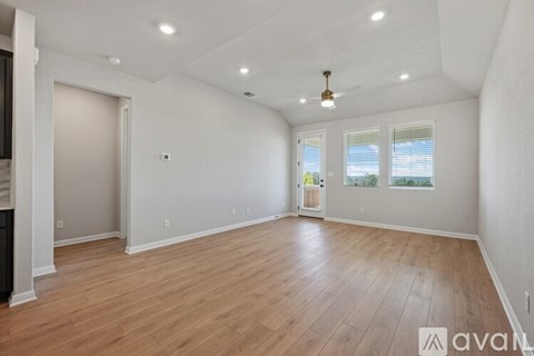 A spacious room with wooden flooring and white walls.
