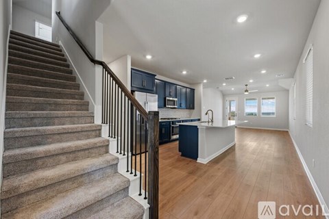 A staircase with a carpeted runner leads up to a kitchen area with dark wood floors.