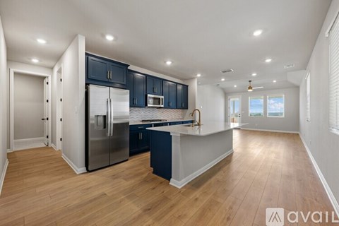 A kitchen with dark blue cabinets and a wooden floor.