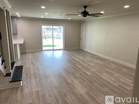 A spacious room with a ceiling fan and light wood flooring.