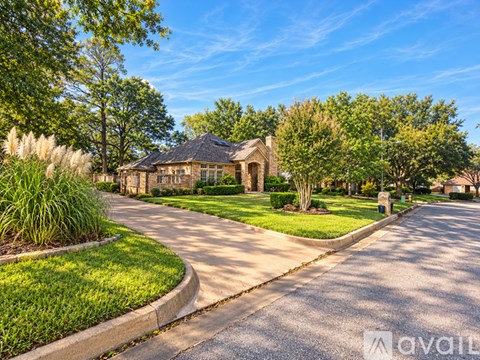A house with a driveway and trees in front of it.