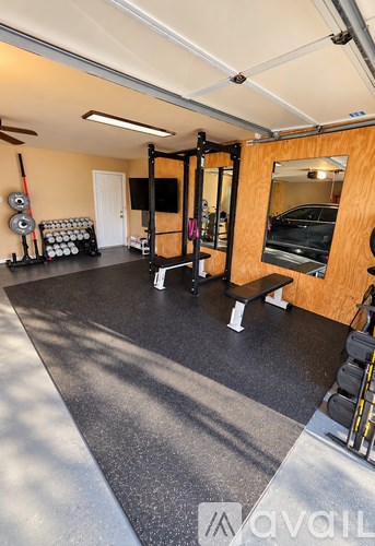 A gym with a bench, weights, and a mirror.