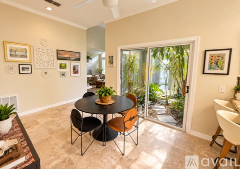A dining room with a table and chairs and a view of a garden outside.