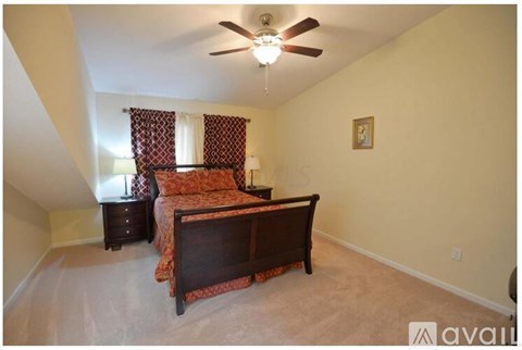 A bedroom with a bed, nightstand, and window with curtains.