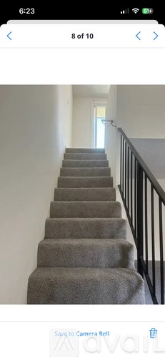 A staircase with a carpeted runner and a black railing.