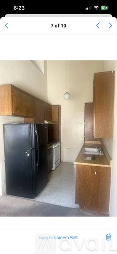A kitchen with a black fridge and wooden cabinets.