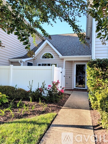 A house with a white fence and a garden in front.