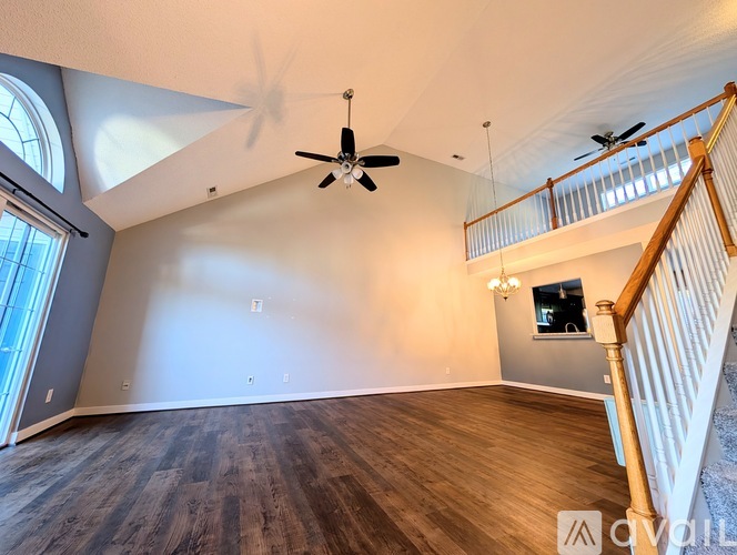 A spacious room with a ceiling fan and wooden flooring.