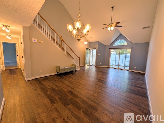 A spacious living room with wood flooring and a staircase leading to the upper level.
