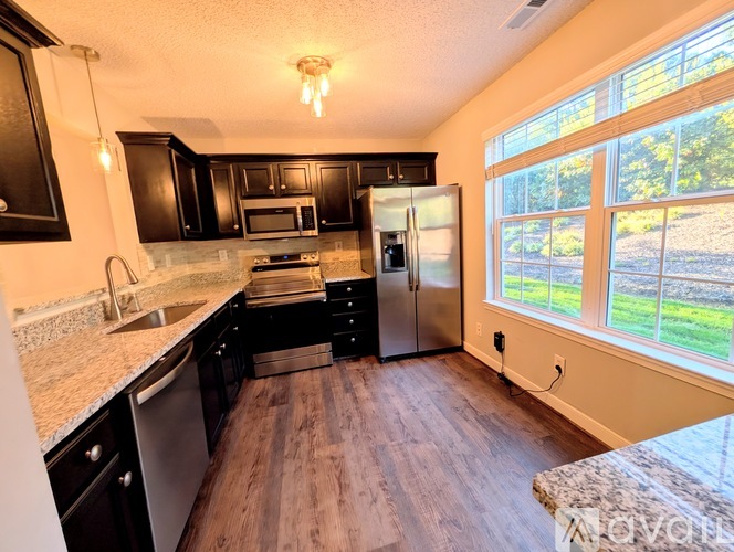 A kitchen with black cabinets and a wooden floor.