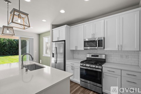 A modern kitchen with white cabinets and stainless steel appliances.