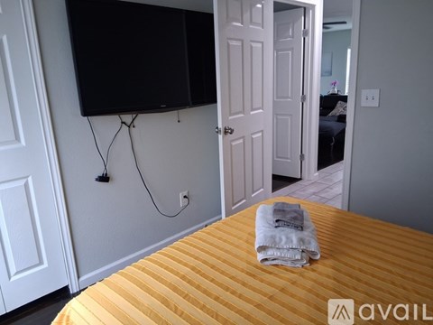 A bed with a yellow cover and a flat screen TV mounted on the wall.