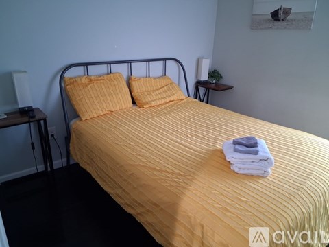 A bed with a yellow comforter and two pillows with a towel on top of it.