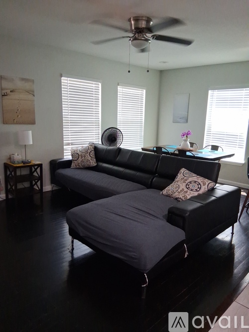 A living room with a black couch and a fan.