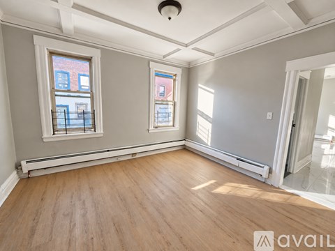 A room with wooden floors and two windows.