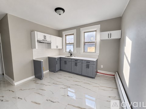 A kitchen with grey cabinets and a white countertop.