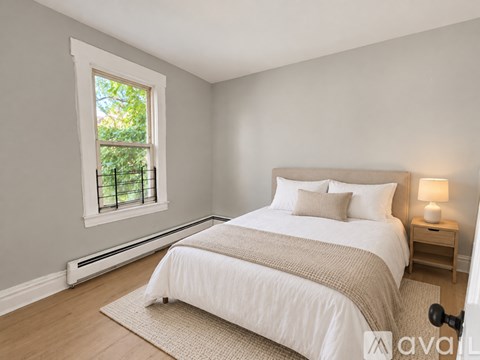 A bedroom with a large bed and a window with a view of trees.