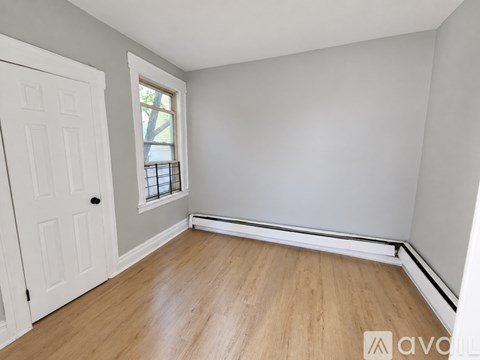 A room with a white door and wooden floor.