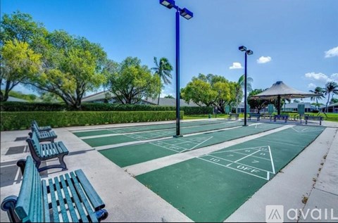 A tennis court with green benches and trees in the background.