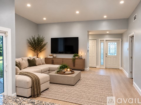 A modern living room with a large couch and a flat screen TV mounted on the wall.