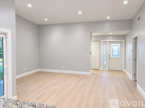 A spacious room with wooden flooring and white walls.