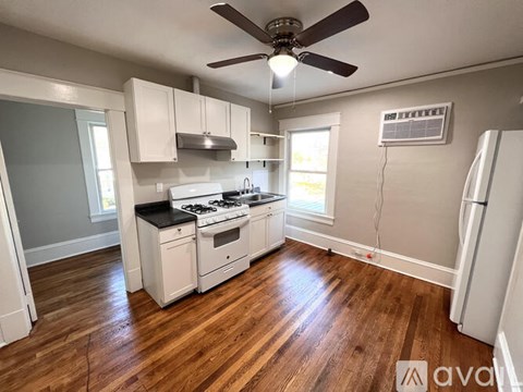 A kitchen with wood floors and white appliances.