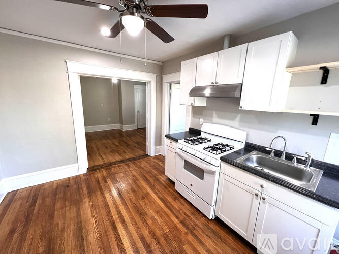 A kitchen with a wooden floor and white cabinets.